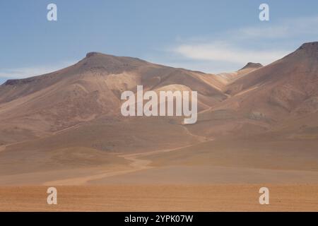 Eine atemberaubende Wüstenlandschaft im bolivianischen Altiplano mit trockenen Ebenen, majestätischen Bergen und einem weiten, klaren blauen Himmel in ruhiger Abgeschiedenheit Stockfoto