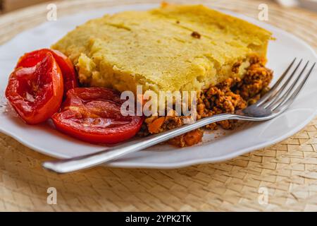 Frisch zubereiteter Hirtenkuchen mit eingelegten Tomaten auf einem weißen Teller Stockfoto