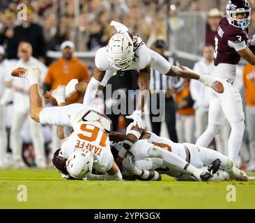 College Station, Texas, USA. November 2024 30. Eine Gruppe von Texas-Verteidigern taucht auf, um Texas A&M, Amari Daniels (5), während der ersten Hälfte des College-Footballspiels zwischen den Texas A&M Aggies und den Texas Longhorns am 30. November 2024 in College Station, Texas, zu bekämpfen. Texas gewann mit 17:7. (Kreditbild: © Scott Coleman/ZUMA Press Wire) NUR REDAKTIONELLE VERWENDUNG! Nicht für kommerzielle ZWECKE! Quelle: ZUMA Press, Inc./Alamy Live News Stockfoto