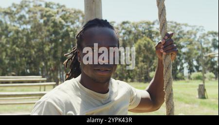 Passen Sie afroamerikanische Soldaten mit Deadlocks, die am Seil auf dem Hinderniskurs der Armee hinunterklettern Stockfoto