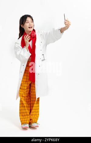 Frau, die einen Windbreaker trägt und Selfies mit ihrem Handy in der Hand nimmt Stockfoto