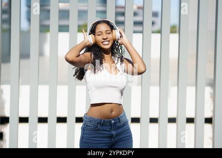 Eine junge Frau genießt fröhlich Musik in einer lebhaften urbanen Umgebung im Freien Stockfoto