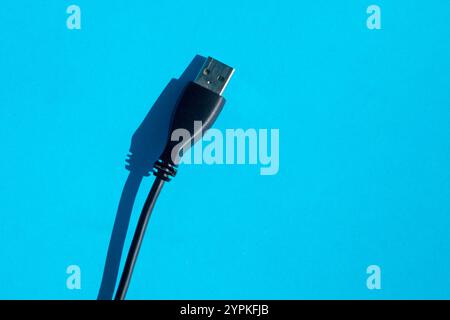 USB-Datenkabel für Mobilgeräte. usb-Anschluss für Telefon auf blauem Hintergrund, usb-Kabel Ladegerät mit Schatten Stockfoto