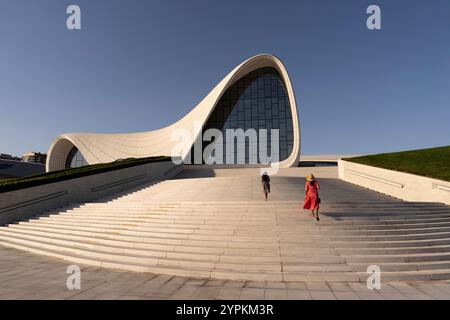 Eine Frau und ihre Tochter steigen die Treppe hinauf, die zum berühmten Heydar Aliyev Center in Baku, Aserbaidschan, führt. Der helle, sonnige Tag betont den Cent Stockfoto