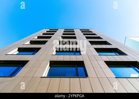 Vertikale Perspektive eines modernen Gebäudes mit reflektierenden Fenstern vor einem klaren blauen Himmel Stockfoto