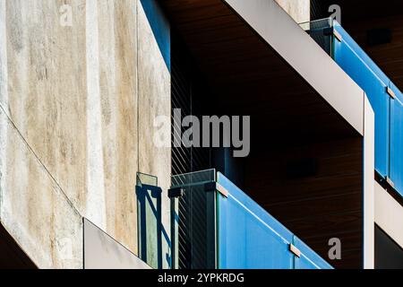 Moderne architektonische Fassade mit geometrischen Vorsprüngen und reflektierenden Fenstern im Sonnenlicht Stockfoto
