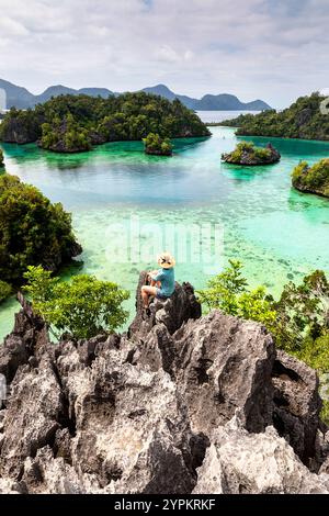 Frau mit Strohhut, die den spektakulären Aussichtspunkt genießt und die Karstlagunen des Sombori-Archipels in sulawesi, indonesien betrachtet Stockfoto