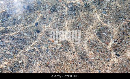 Seesteine. Klares, transparentes Wasser und Wellen an sonnigen Tagen mit viel Sand und Steinen. Stockfoto