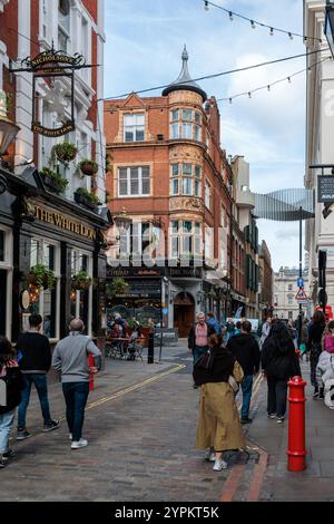 Historisches White Lion Pub und viktorianische Architektur im Londoner Covent Garden, mit festlichen Lichtern und geschäftiger Straßenszene, die typisch urbanes Leben zeigen Stockfoto