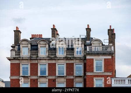 Viktorianische Wohnarchitektur mit verzierten Dachfenstern, roter Backsteinfassade und dekorativen Brüstungen in der Nähe von Covent Garden, London Stockfoto