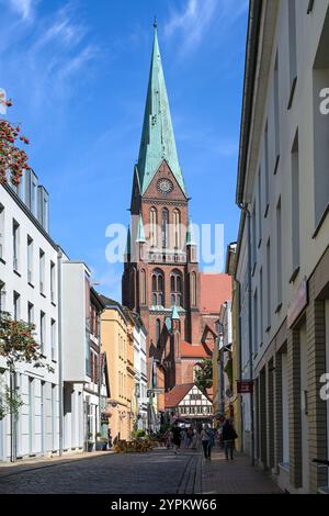 Schwerin, Deutschland, 29. Juli 2024: Die schmale Buschstraße mit kleinen Geschäften und Straßenrestaurants führt zum St.-Marien-Dom im historischen Ol Stockfoto