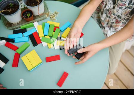 Ein Kind spielt eine spielerische Aktivität und baut mit bunten Holzblöcken auf einem runden Tisch. Die Szene ist voller Kreativität und Spaß Stockfoto