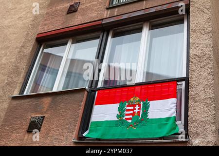 Ungarische Flagge hängt am Fenster in einem Gebäude. Die Flagge hat drei horizontale Streifen mit doppeltem Kreuz. Flag steht für Hung Stockfoto