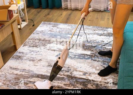 Frau, die den Teppich mit einem Staubsauger reinigt. Stockfoto