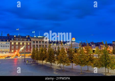 Abendlicher Blick auf Kongens Nytorv in Kopenhagen, Dänemark, mit beleuchteten historischen Gebäuden, pulsierenden Stadtlichtern und einem tiefblauen Himmel Stockfoto