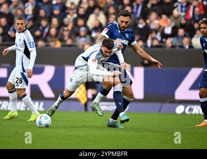 1. Dezember 2024, Baden-Württemberg, Karlsruhe: Fußball: Bundesliga 2, Karlsruher SC - Hamburger SV, Spieltag 14, BBBank Wildpark. Karlsruher Fabian Schleusener (r) und Hamburgs William Mikelbrencis kämpfen um den Ball. Foto: Uli Deck/dpa - WICHTIGER HINWEIS: Gemäß den Vorschriften der DFL Deutschen Fußball-Liga und des DFB Deutschen Fußball-Bundes ist es verboten, im Stadion und/oder im Spiel aufgenommene Fotografien in Form von sequenziellen Bildern und/oder videoähnlichen Fotoserien zu verwenden oder zu nutzen. Stockfoto