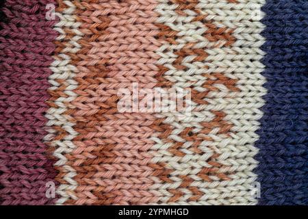 Handgefertigte Strickstruktur mit blauer, brauner, dunkelroter und weißer Wolle. Stockfoto