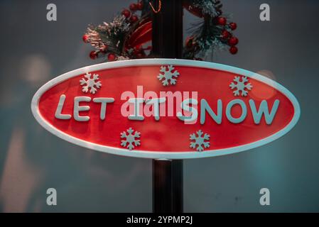 Der Weihnachtsmann und ein Schneemann stehen unter einer leuchtenden Straßenlaterne, bedeckt von Schnee. Die festliche Dekoration und die schneebedeckte Umgebung schaffen zauberhafte Weihnachten Stockfoto