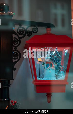 Der Weihnachtsmann und ein Schneemann stehen unter einer leuchtenden Straßenlaterne, bedeckt von Schnee. Die festliche Dekoration und die schneebedeckte Umgebung schaffen zauberhafte Weihnachten Stockfoto