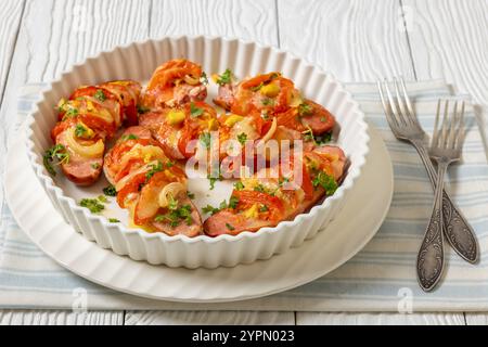 Uunimakkara, gebacken im Ofen Würstchen mit Käse, Tomaten, Senf in Backform auf weißem Holztisch mit Gabeln, finnisches klassisches Rezept, schließen Stockfoto