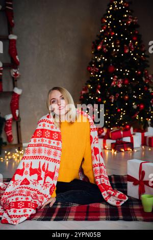Schöne blonde Frau am Weihnachtsbaum mit Geschenken, Spielzeug, Girlanden für das neue Jahr Stockfoto