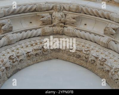 Komplexe Steinschnitzereien zeigen historische Handwerkskunst auf einem Gebäude in Spanien. Der dekorative Bogen ist mit detaillierten Figuren und Blumenmotiven versehen Stockfoto