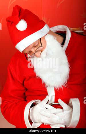 Der müde weihnachtsmann schläft auf einem Stuhl Stockfoto