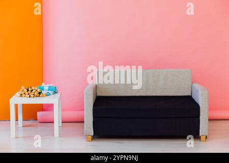 Schwarz-graues Bürosofa und Blumen an rosafarbenen Wänden Stockfoto