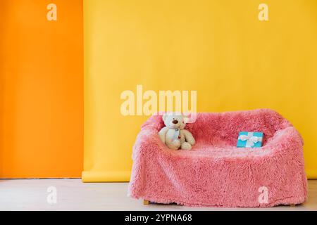 Rosafarbenes Sofa Mit Geschenken Gegen Gelb-Orange Wand Stockfoto