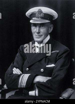 Ein formelles Porträt von Sir Humphry Davy Rolleston in Marineuniform, aufgenommen 1916, fängt den renommierten englischen Arzt während seines Dienstes der Royal Navy im Ersten Weltkrieg ein. Der 1862 geborene Rolleston war ein führender Experte für Lebererkrankungen und verfasste einflussreiche medizinische Texte. 1920 wurde er zum Ritter geschlagen und war später Präsident des Royal College of Physicians, wo er sich für öffentliche Gesundheit und medizinische Ausbildung einsetzte. Seine Beiträge zur Medizin und sein Vermächtnis als Gelehrter und Kliniker sind nach wie vor bedeutsam. Stockfoto