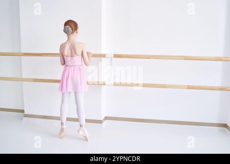 Ein junges Ballettmädchen beim Studiounterricht. Trainingsleistung. Stretching-Übungshaltung. Ballerina-Praxis-Balance-Technik. Klassische Eleganz Fitness. Tanzkostüm. Rosafarbenes Kleid. Punkt. Aufstehen Stockfoto