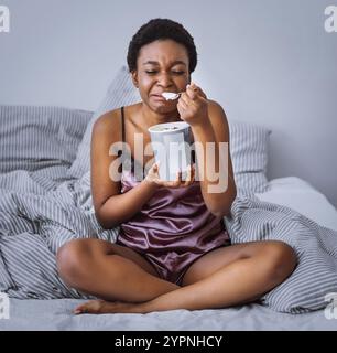Zerfall Konzept. Weinendes Mädchen, das Eis im Bett isst Stockfoto