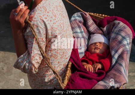 Sikkim, Indianer - 22. März 2004 : Sikkimese Mutter trägt ihr Baby auf dem Rücken. Großmutter beobachtet das Baby. Mütter in Sikkim arbeiten hart. Stockfoto