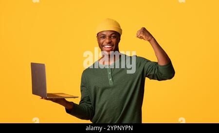 Online Gewinnen. Überglücklich schwarzer Kerl hält Laptop und feiert Erfolg Stockfoto