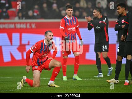 1. Dezember 2024, Baden-Württemberg, Heidenheim: Fußball: Bundesliga, 1. FC Heidenheim - Eintracht Frankfurt, Spieltag 12, Voith-Arena. Heidenheims Jonas Föhrenbach (l) und Heidenheims Mathias Honsak sind frustriert, nachdem sie ein Tor zugestanden haben, während die Frankfurter Spieler jubeln. Foto: Jan-Philipp Strobel/dpa - WICHTIGER HINWEIS: Gemäß den Vorschriften der DFL Deutschen Fußball-Liga und des DFB Deutschen Fußball-Bundes ist es verboten, im Stadion und/oder im Spiel aufgenommene Fotografien in Form von sequenziellen Bildern und/oder videoähnlichen Fotoserien zu verwenden oder zu verwenden. Stockfoto