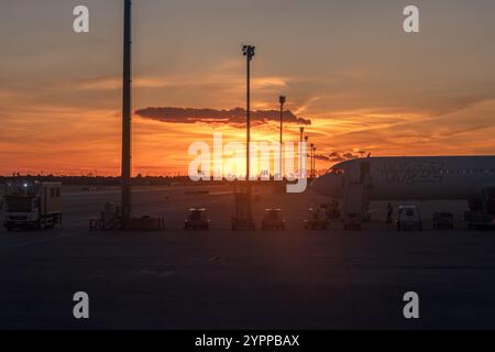 Eindrucksvoller Blick bei Sonnenuntergang auf die Start- und Landebahn am Flughafen Barcelona-El Prat. Im Vordergrund steht ein Verkehrsflugzeug der Billigfluggesellschaft Wizz Air. Stockfoto