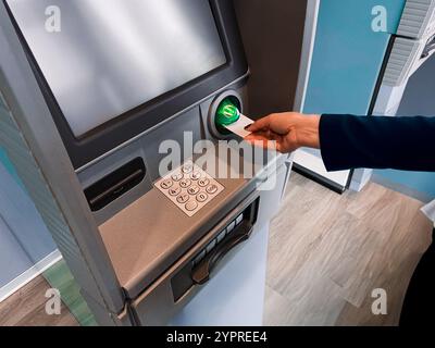 Frau, die Geld am Geldautomaten abhebt. Mit Debitkarte vom Bankkonto abheben. Sicherer Bankautomat. Bargeld vom Geldautomaten abheben. Finanziell Stockfoto