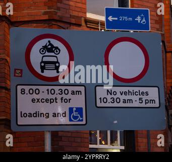 Straßenschilder mit Fahrzeugbeschränkungen und Ladezeiten vor dem Hintergrund des roten Backsteingebäudes York UK Stockfoto