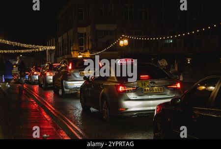 Eine Reihe von Autos, die in einer nassen Nacht über die Ouse Bridge York fahren, mit festlichen Lichtern, die die Szene beleuchten und im November 2024 eine gemütliche Atmosphäre schaffen Stockfoto