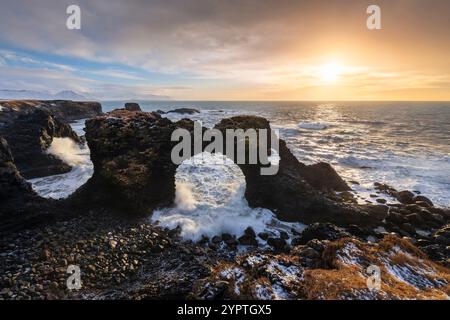 Blick auf den Felsbogen Gatklettur bei Sonnenaufgang im Winter. Arnarstapi, Hellnar, Halbinsel Snæfellsnes, Island, Nordeuropa. Stockfoto