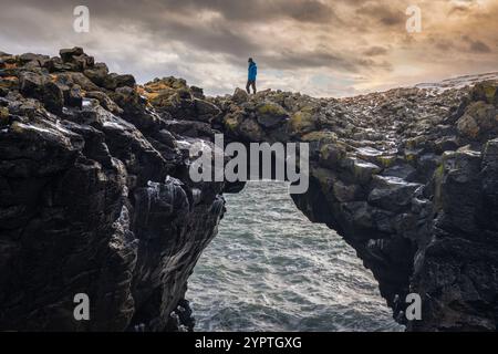 Blick auf einen Mann, der auf der Steinbrücke steht. Arnarstapi, Halbinsel Snæfellsnes, Island, Nordeuropa. Stockfoto