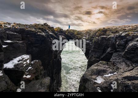 Blick auf einen Mann, der auf der Steinbrücke steht. Arnarstapi, Halbinsel Snæfellsnes, Island, Nordeuropa. Stockfoto