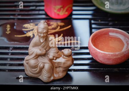 Fragment der Teezeremonie mit Fokus auf die Keramikfigur des Salbei des Tees Lu Yu im Vordergrund. Klassische chinesische Teekultur Stockfoto