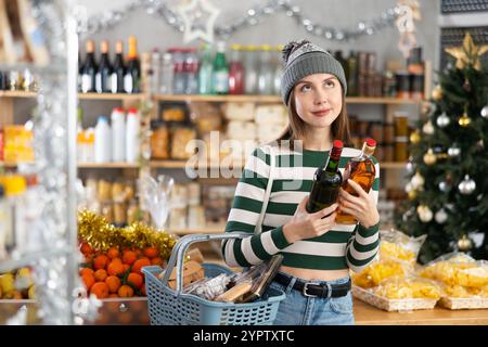 Junge Frau untersucht Alkohol Whisky Flasche im Laden. Stockfoto