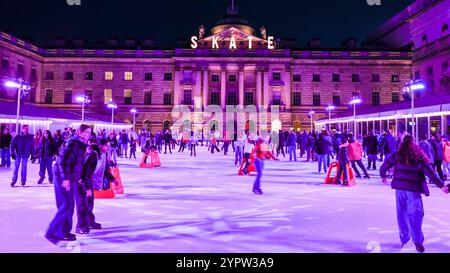 London, Großbritannien. Dezember 2024. Die Eislaufbahn im Somerset House sieht mit ihren farbenfrohen Lichtern hübsch aus, während die Menschen ihr festliches Schlittschuhlaufen auf dem Gelände des historischen Wahrzeichens genießen. Quelle: Imageplotter/Alamy Live News Stockfoto