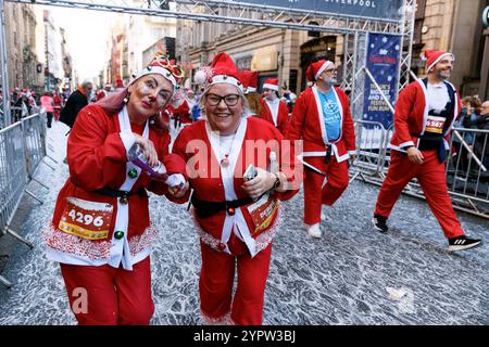 Liverpool, Großbritannien. Dezember 2024. Läufer auf der Ziellinie des Liverpool Santa Dash 2024. Die Teilnehmer trafen in roten (und blauen) Santa Suits auf einer 5 km langen Strecke durch das Stadtzentrum von Liverpool, um das Claire House Kinderhospiz zu unterstützen. 8.500 Teilnehmer nahmen am 20. Jährlichen Liverpool Santa Dash Teil. (Credit Image: © Andy von Pip/SOPA Images via ZUMA Press Wire) NUR REDAKTIONELLE VERWENDUNG! Nicht für kommerzielle ZWECKE! Stockfoto