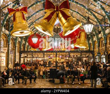 London, Großbritannien. Dezember 2024. Die ehemaligen Markthallen von Covent Garden sind mit riesigen Bögen und Kugeln dekoriert, während die Käufer in Geschäften und entlang der kleinen Verkaufsstände des überdachten Apple Market nach Weihnachtsgeschenken suchen. Quelle: Imageplotter/Alamy Live News Stockfoto