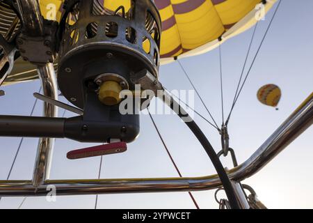 Nahaufnahme des Brennersystems eines bunten gelben Heißluftballons von unten Stockfoto