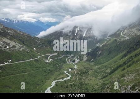 Situation am Furka Pass an einem bewölkten Sommertag. Blick in das Rhonetal mit Bergpässen. Wolken strömen von Norden über den Grimselpass Stockfoto