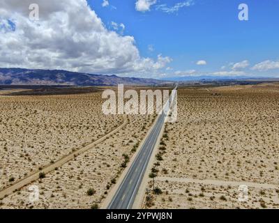 Aus der Vogelperspektive auf die endlose Wüste, gerade staubige Asphaltstraße im Joshua Tree Park. USA. Lange, gerade asphaltierte Straße in die Wüste in Richtung Stockfoto